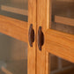Maple Corner Woodworks Cherry Moon Bookcase crafted in Vermont from sustainable cherry wood, featuring glass doors and elegant curved handles.