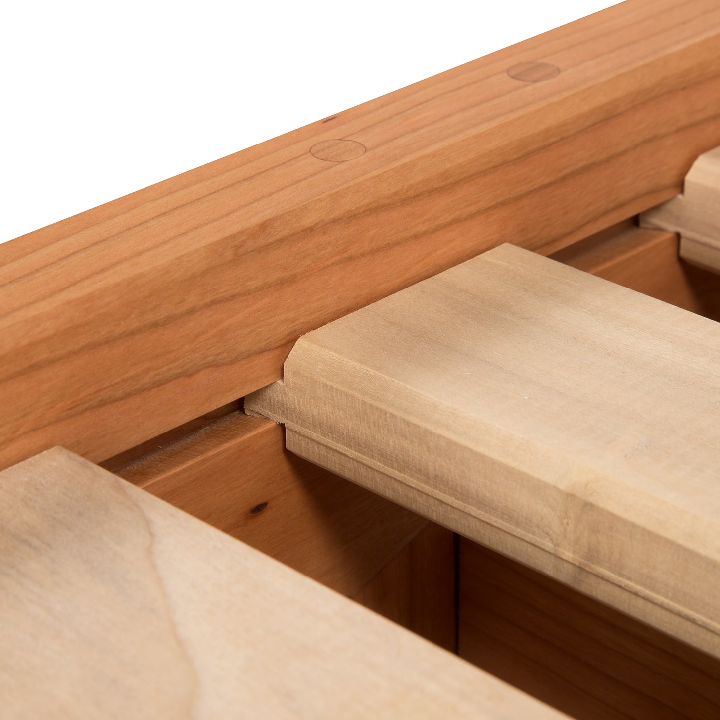 Close-up of a wooden drawer partially opened, showing the craftsmanship with visible dovetail joints and wood grain texture. An eco-friendly oil finish enhances the Maple Corner Woodworks Cherry Moon Dovetail Platform Bed detail against a neutral background.
