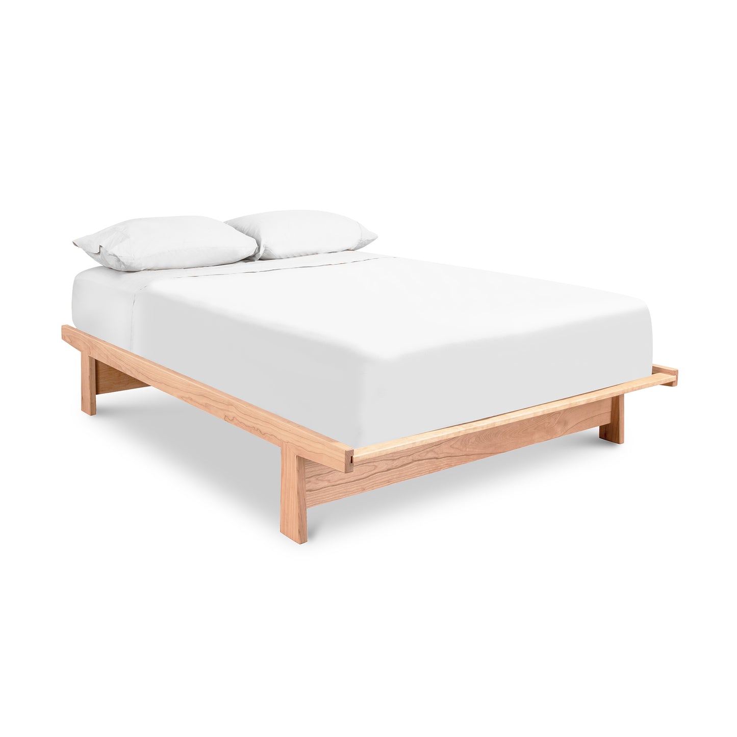 A simple Maple Corner Woodworks Cherry Moon Dovetail Platform Bed with a white mattress and two pillows, isolated on a white background.