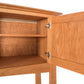 Interior view of an open Maple Corner Woodworks Cherry Moon Huntboard showing empty shelves and the door's hinge mechanism against a plain background.