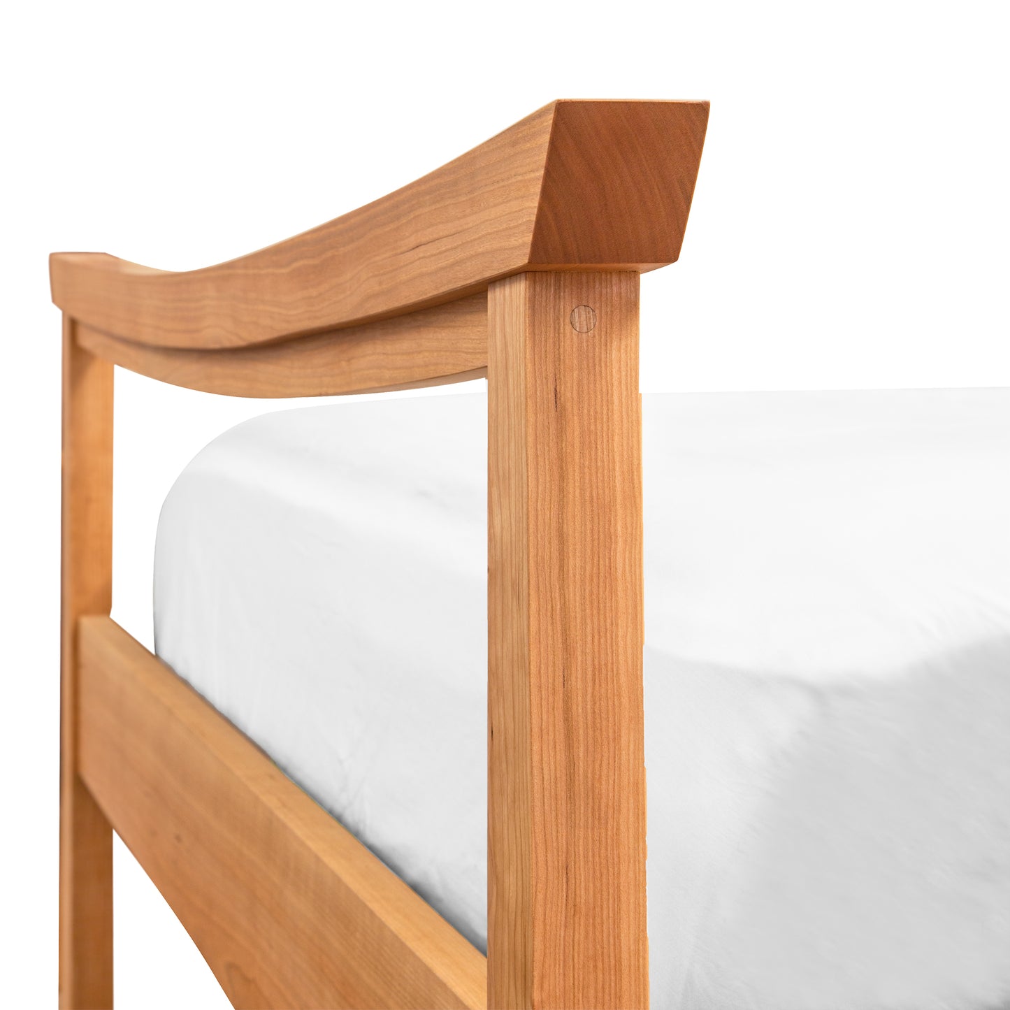 A close-up of a Maple Corner Woodworks Cherry Moon Pagoda Bed frame’s headboard featuring a curved top rail and vertical post, made from natural cherry hardwood, set against a white background with a partially visible white mattress