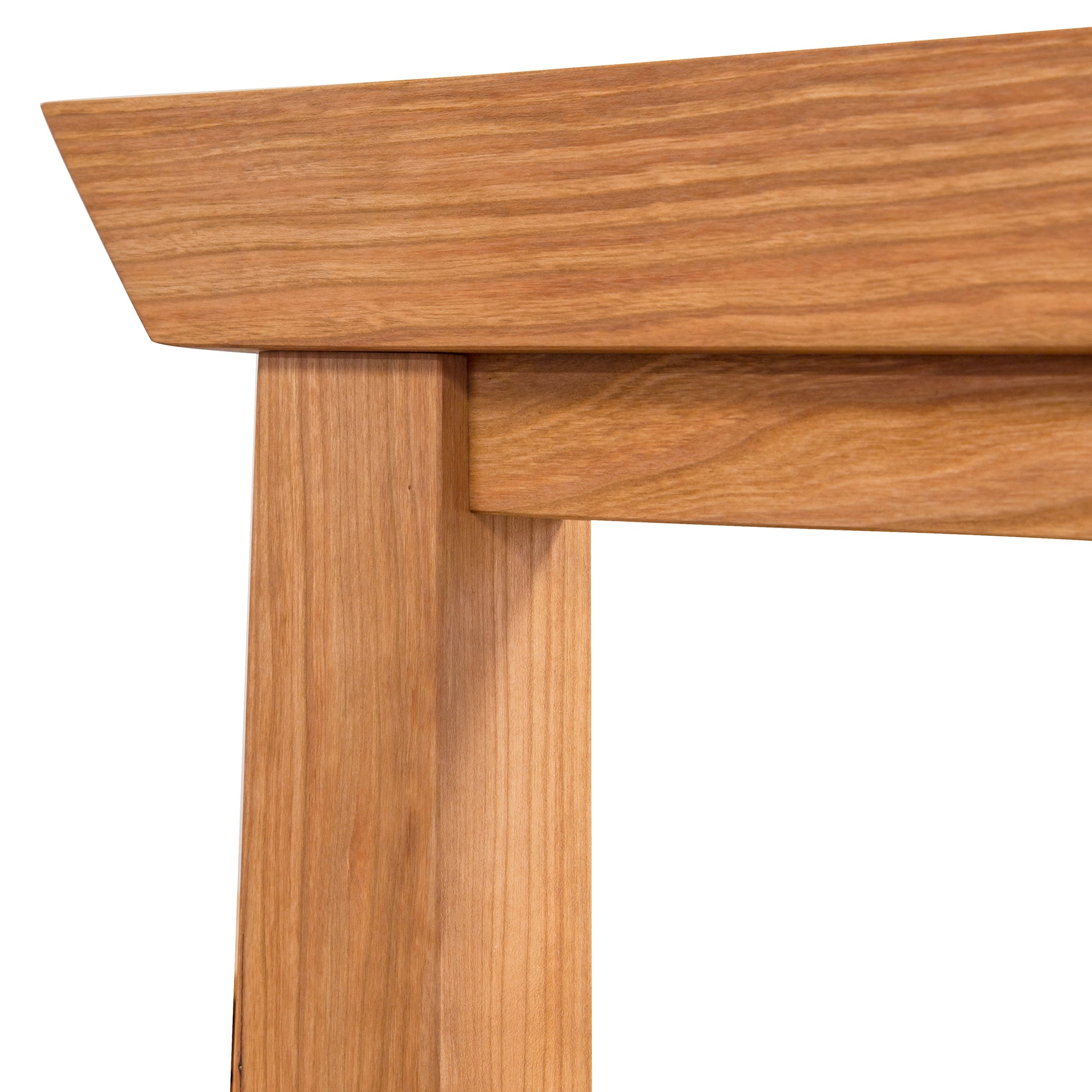 Close-up of a Maple Corner Woodworks Cherry Moon Pagoda Bed showing the smooth, finely finished horizontal top surface meeting the vertical leg at a right angle, highlighting the natural wood grain.