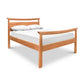 A simple Maple Corner Woodworks Cherry Moon Pagoda Bed frame with a headboard influenced by eastern designs, featuring a white mattress and two pillows on a plain white background.