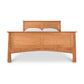 A Maple Corner Woodworks Cherry Moon Panel Bed with a curved headboard and two white pillows, isolated against a white background. The bed features distinct wood grain patterns and a footboard.