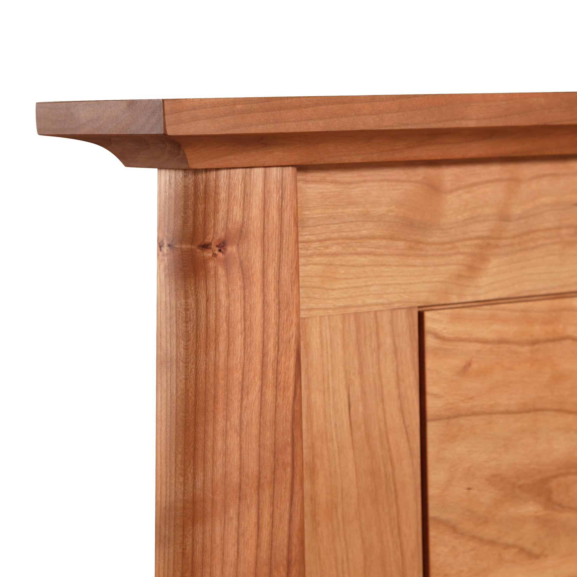 Close-up view of a Cherry Moon Panel Bed from Maple Corner Woodworks corner showing detailed joinery, including a seamless overlapping edge and a vertical panel with wood grain details on a white background.