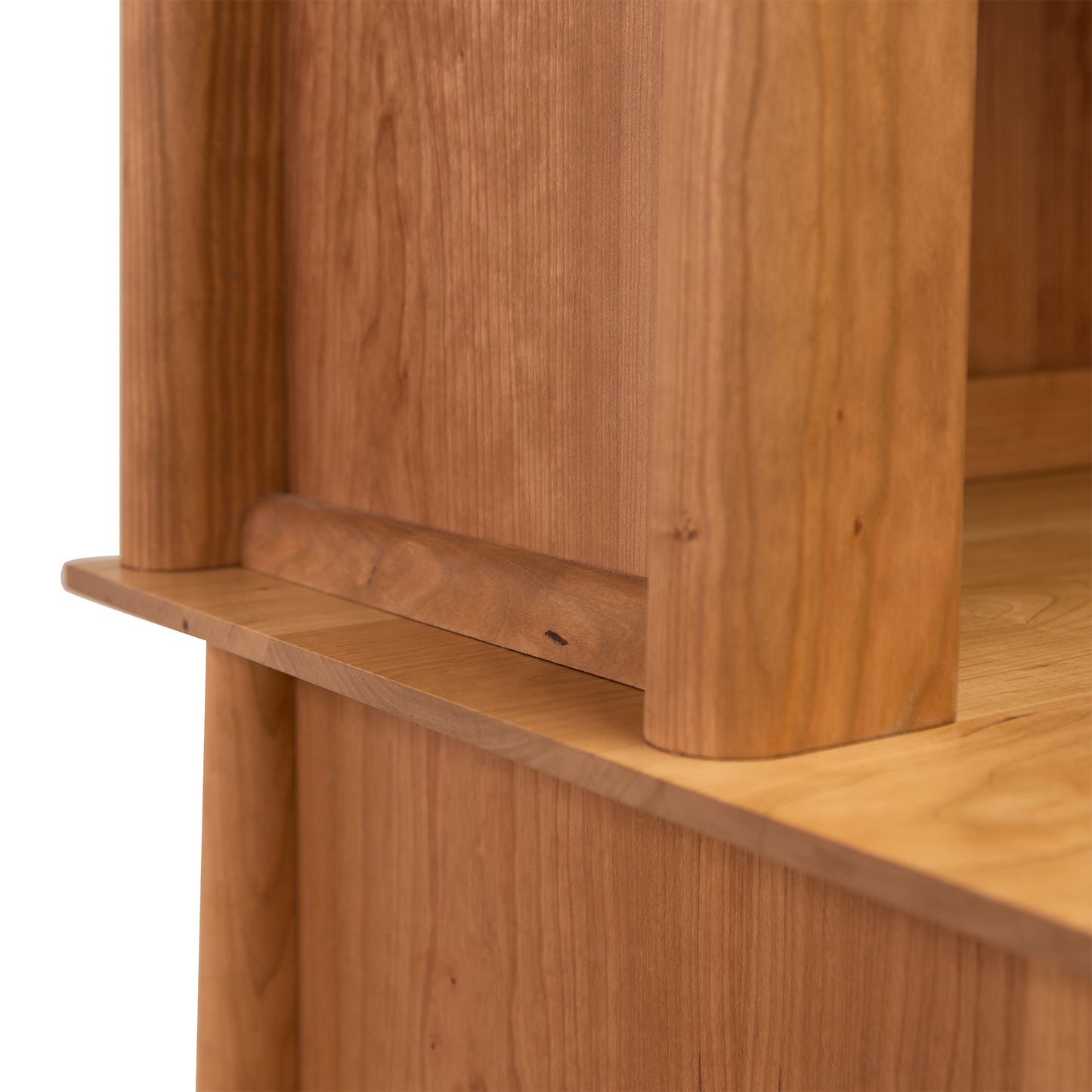 Close-up of a Maple Corner Woodworks Cherry Moon Small China Cabinet with visible grain, showcasing seamless joinery against a light background.