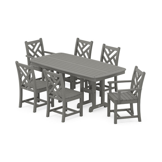 A modern outdoor dining set consisting of a rectangular table and six chairs with geometric backrest designs in the style of POLYWOOD® Chippendale, all in matching grey. The furniture is arranged on a POLYWOOD Chippendale 7-Piece Dining Set.