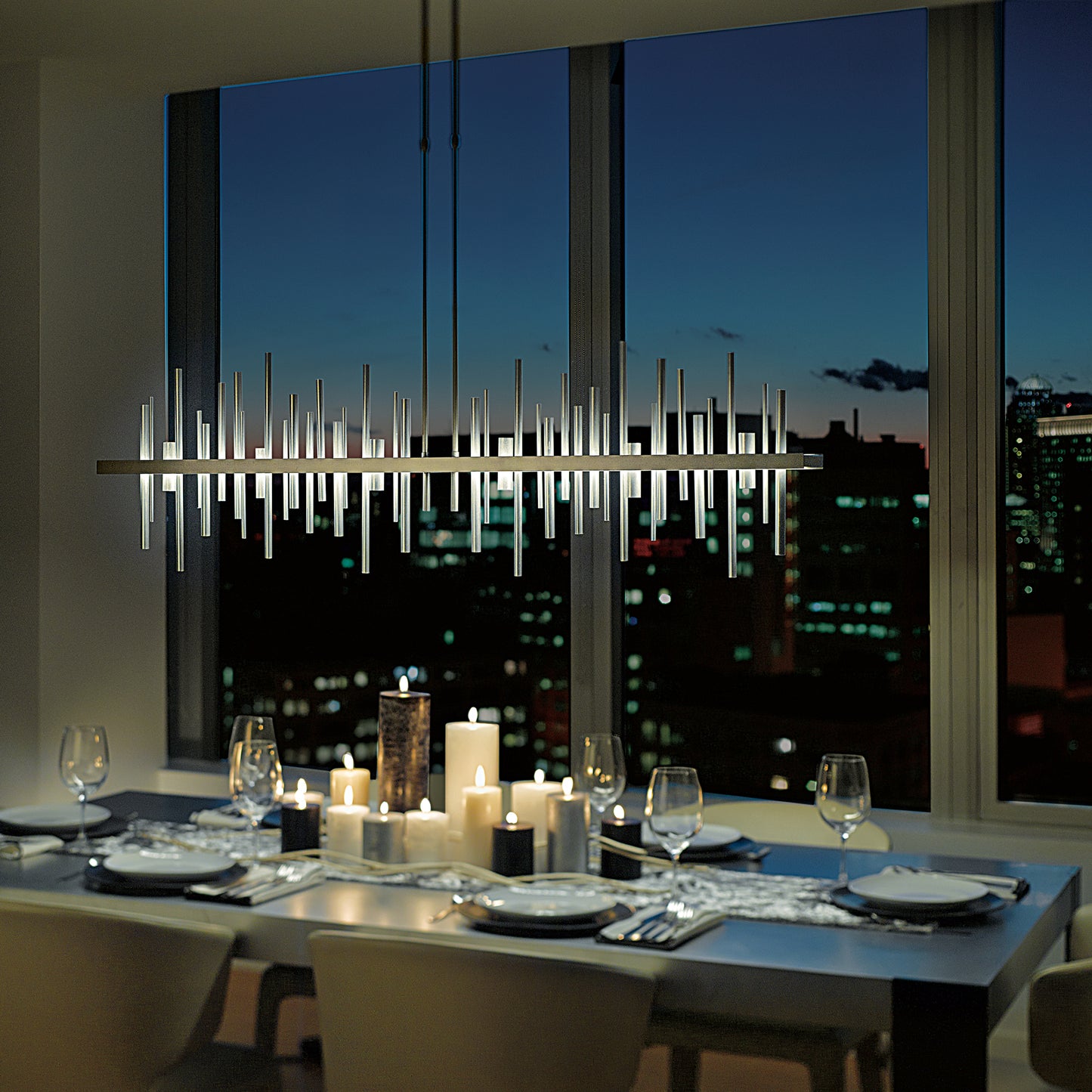 A dining room table with a view of a Hubbardton Forge Cityscape Large LED Pendant, providing an urban panorama of the city.