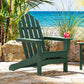 A POLYWOOD Classic Adirondack Chair in green, constructed from durable POLYWOOD lumber, is positioned on a stone patio with an ocean view. A drink garnished with an orange slice and cherry sits on the armrest as plants and rocks nearby enhance the laid-back, beachside ambiance.