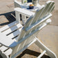 A POLYWOOD Classic Adirondack Chair, crafted from durable POLYWOOD® Lumber, graces the stone patio in a sleek white finish. In the background, a small table holds a refreshing drink, a snack, and potted plants. Sunlight dances across this outdoor furniture, casting gentle shadows on the chair and patio.