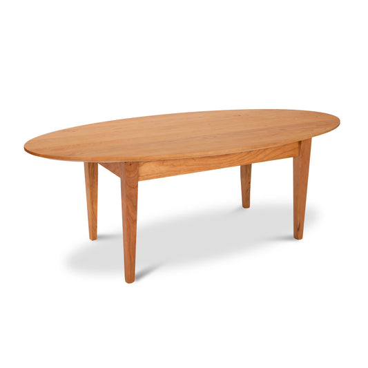 Alt text: Classic Shaker Oval Coffee Table by Lyndon Furniture made of sustainable light brown wood with a minimalist design and tapered legs. High-quality American-made solid wood furniture with smooth edges appealing to mid century modern and Shaker furniture enthusiasts.