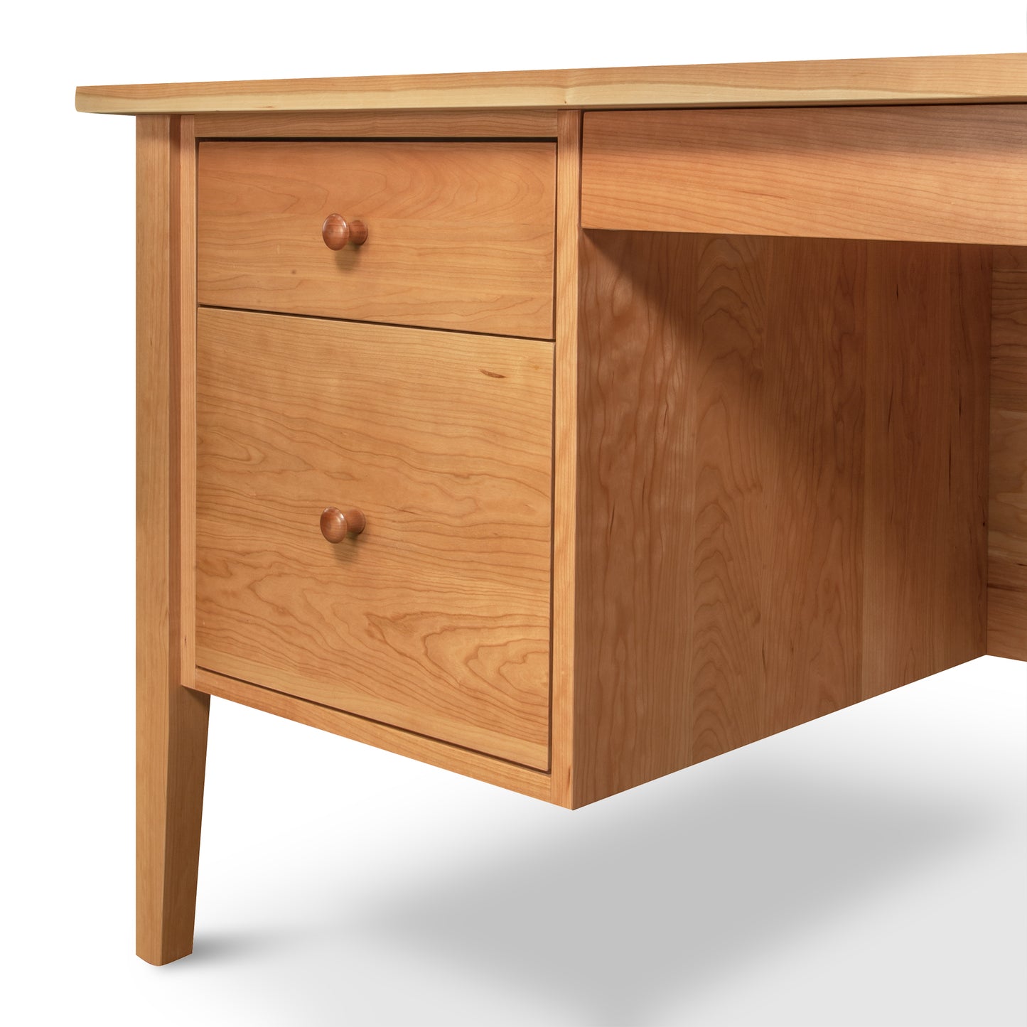 The Lyndon Furniture Small Wood Executive Desk, crafted from solid American wood with a natural finish, features two drawers with round wooden knobs on the left side. Supported by four sturdy legs, this high-quality desk offers a flat surface and simple clean lines, with a subtle grain pattern in the drawers highlighting its texture. Ideal for those seeking American made furniture and solid wood office desks.