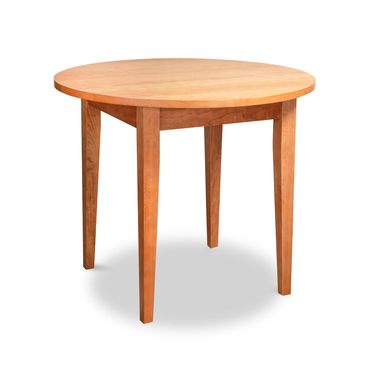 Lyndon Furniture Classic Shaker Round Solid Top Dining Table crafted with a solid hardwood top and tapered legs.