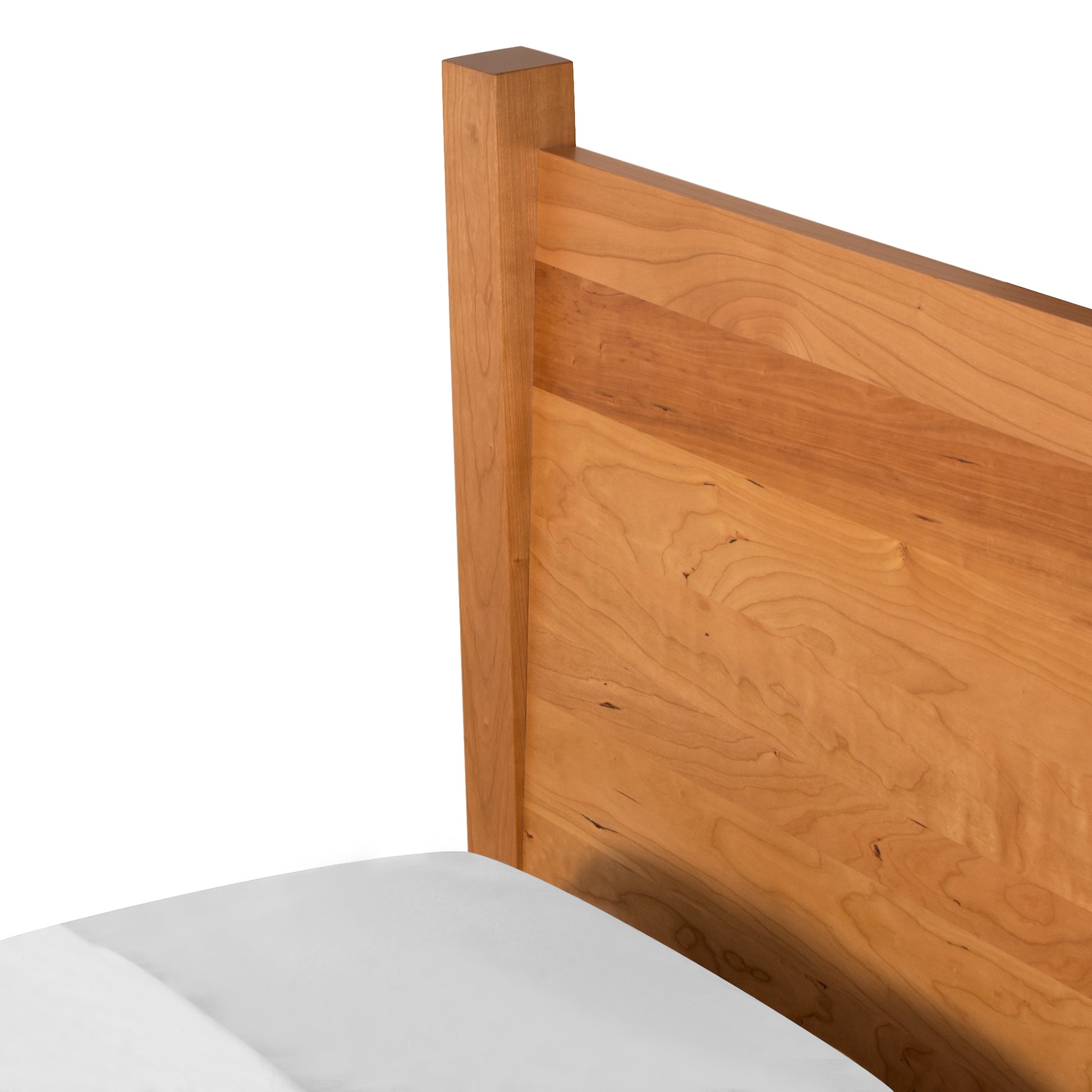A close-up view of a Lyndon Furniture Classic Wood Bed - Queen - Display Model corner and a portion of a white mattress, set against a white background.