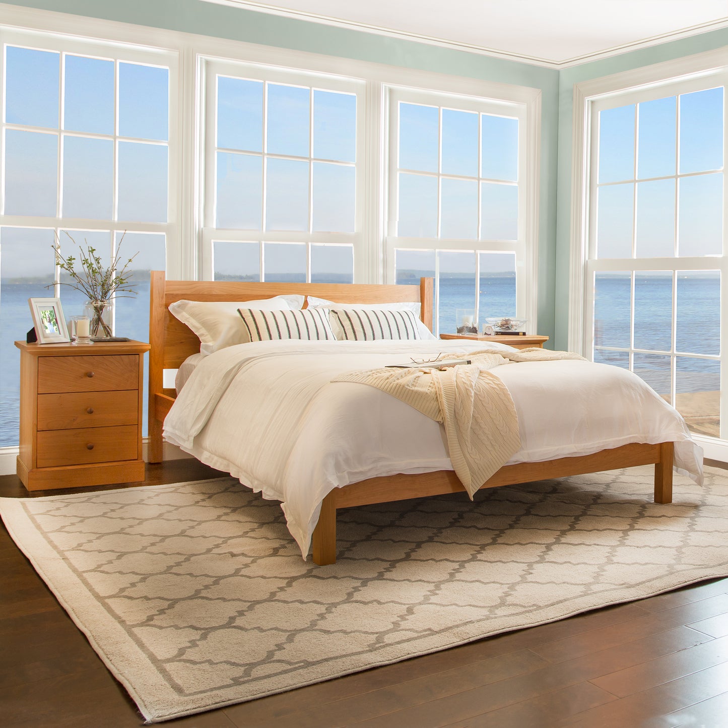 A Classic Wood Bed by Lyndon Furniture in a room with a view of the ocean.