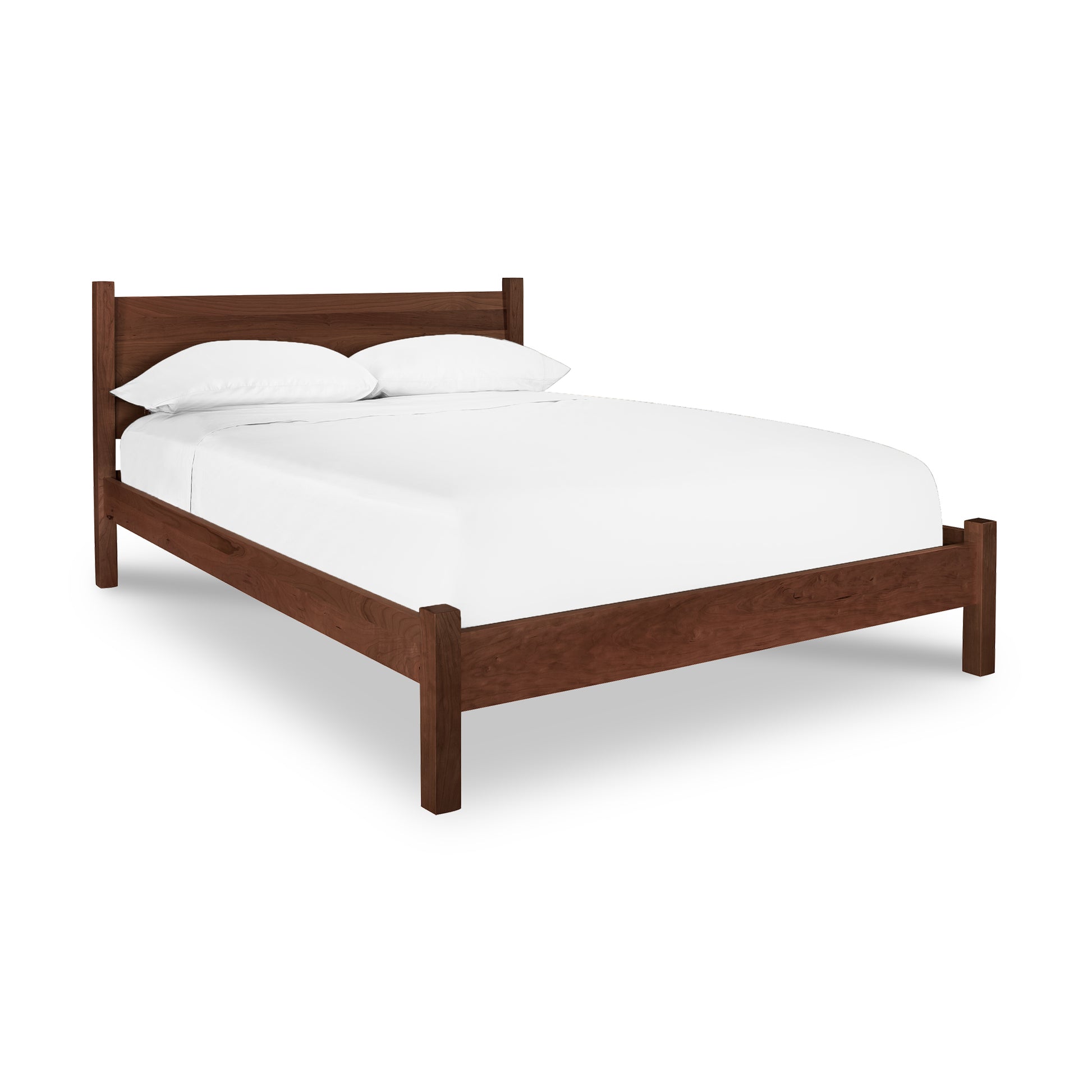 A Lyndon Furniture Classic Wood Bed handcrafted in Vermont, featuring a sustainably harvested wooden frame and adorned with white sheets.