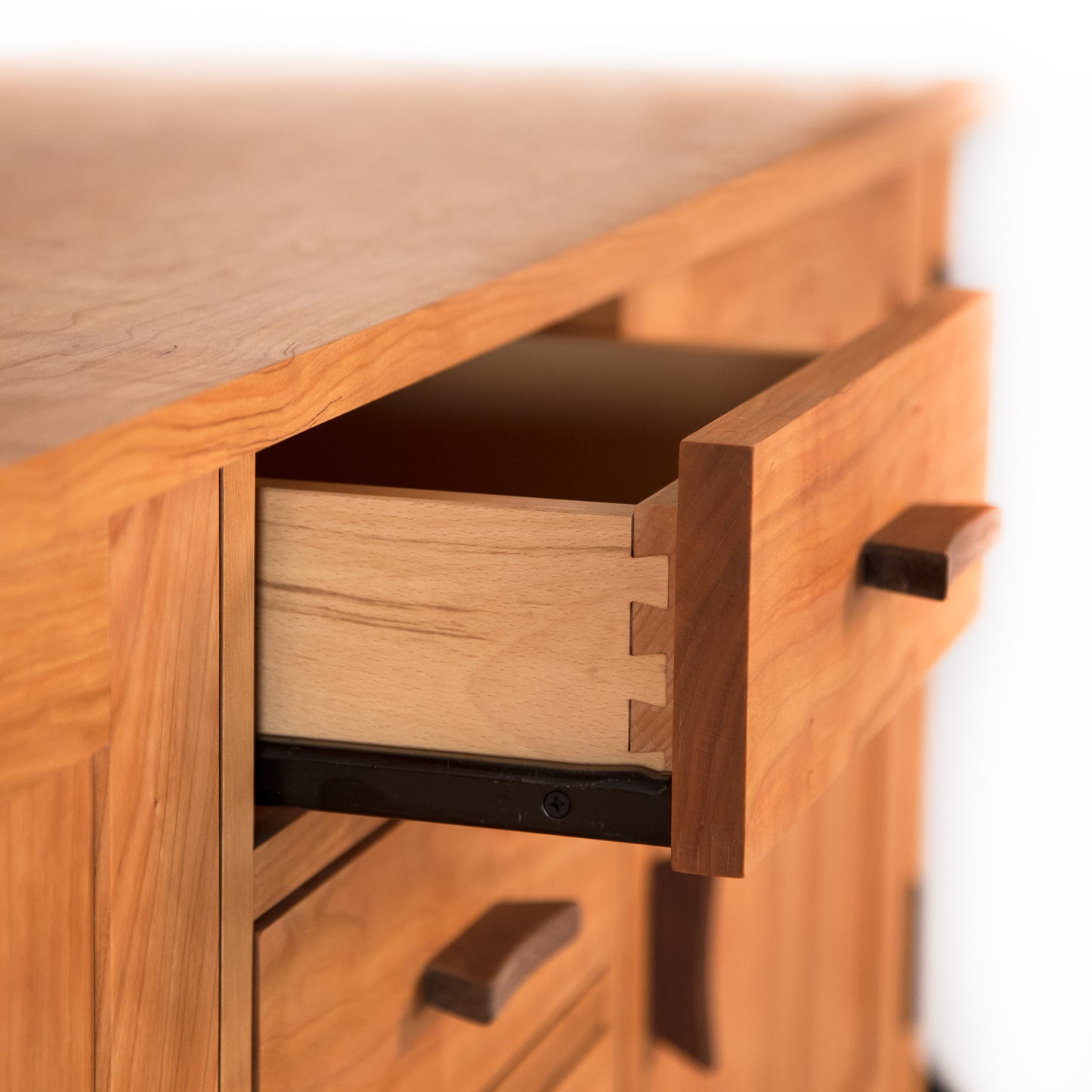 A close up of a drawer in a wooden cabinet, showcasing the impeccable craftsmanship of the Contemporary Craftsman Huntboard by Vermont Furniture Designs.