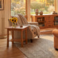 A beige armchair and Vermont Furniture Designs lamp table showcase fine American craftsmanship, highlighted in natural sunlight.