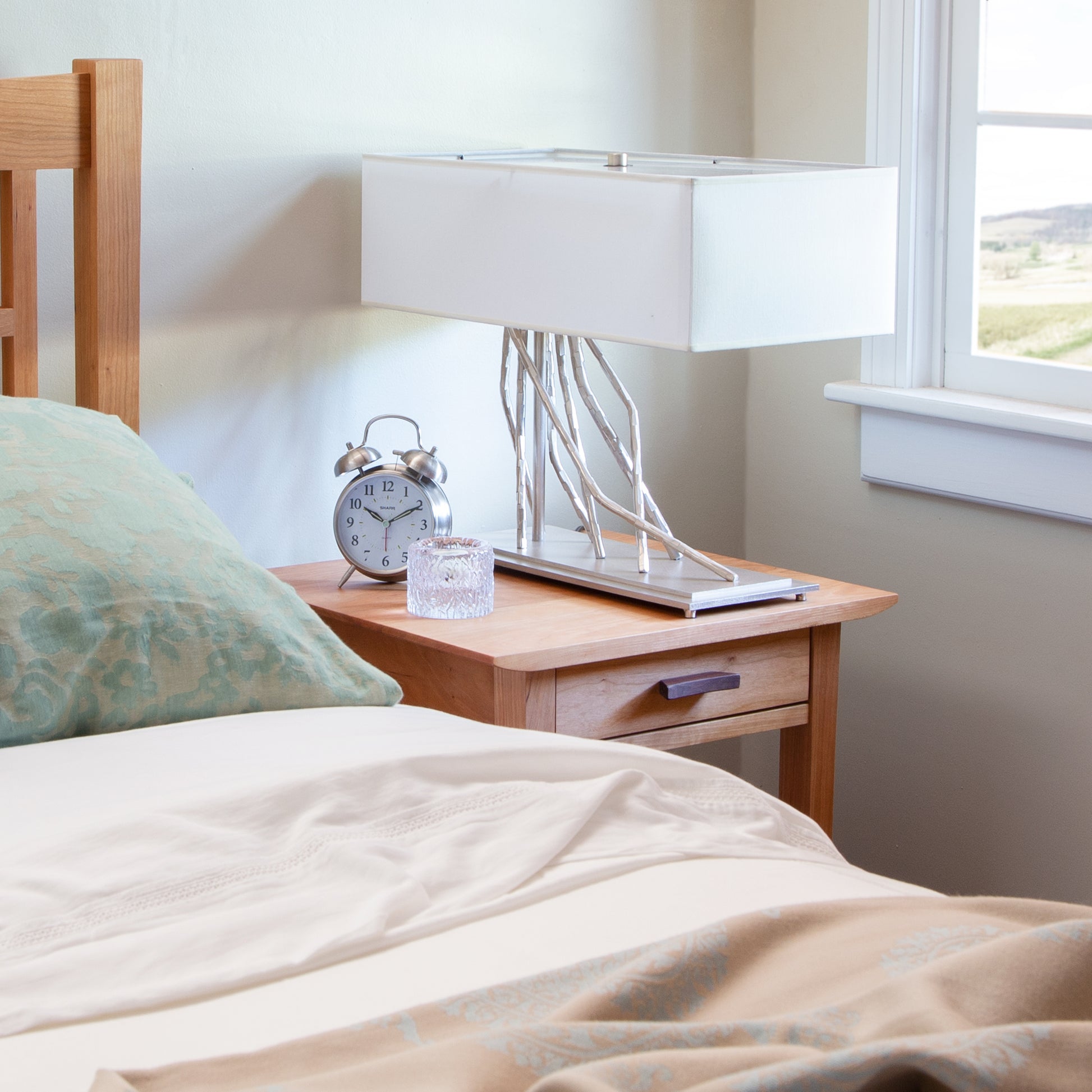 Vermont Furniture Designs nightstand featuring a clock, lamp, and candle holder.