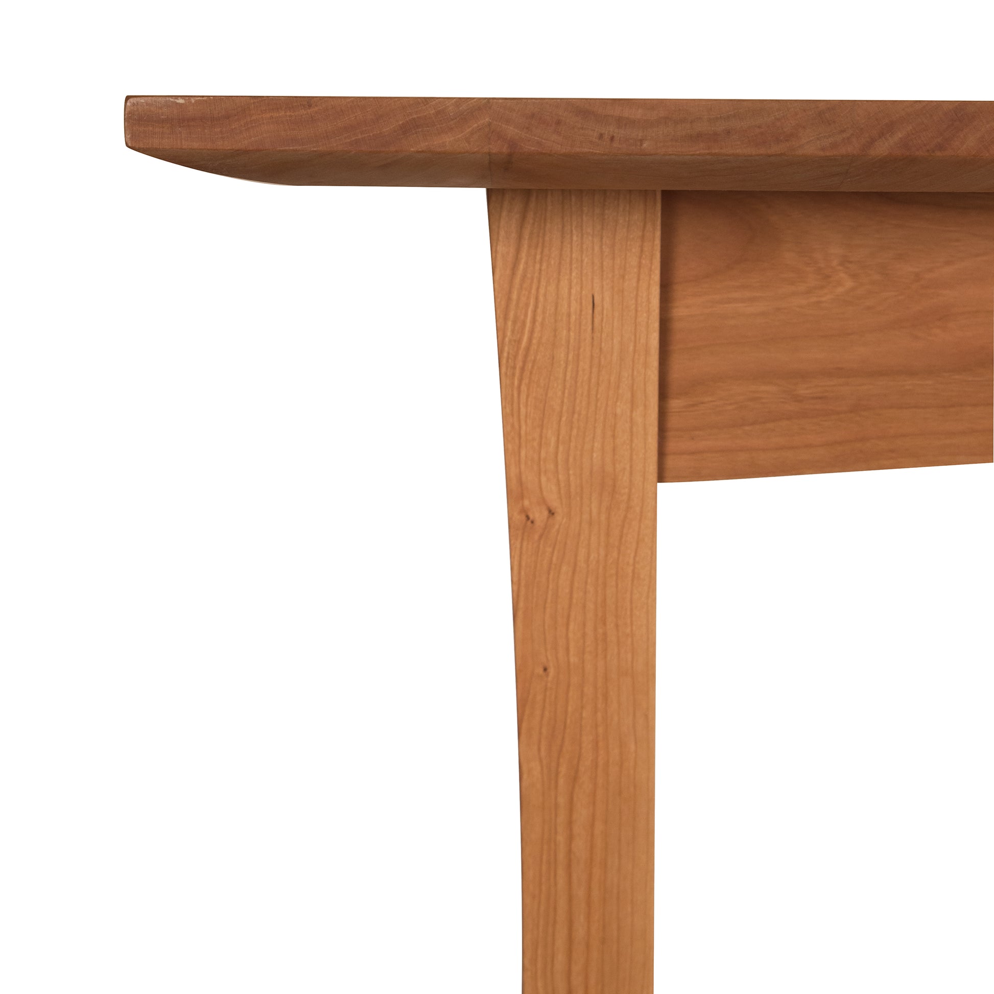 Vermont woodworkers crafted this Contemporary Craftsman Solid Top Dining Table from Vermont Furniture Designs, showcasing a wooden table corner that includes the tabletop and one leg against a white background.