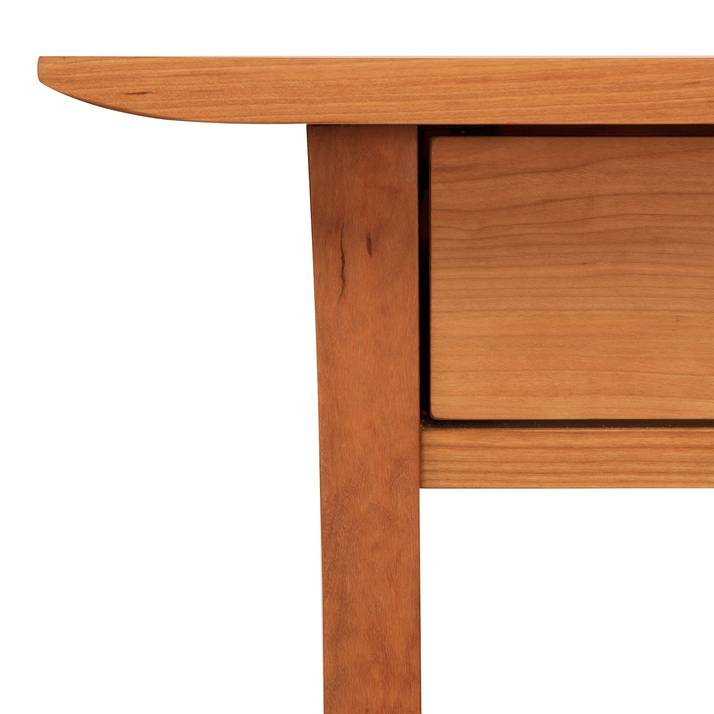 Close-up of a wooden table corner with Arts and Crafts styling, showcasing the wood grain and joinery details against a white background for the Vermont Furniture Designs' Contemporary Craftsman Writing Desk.