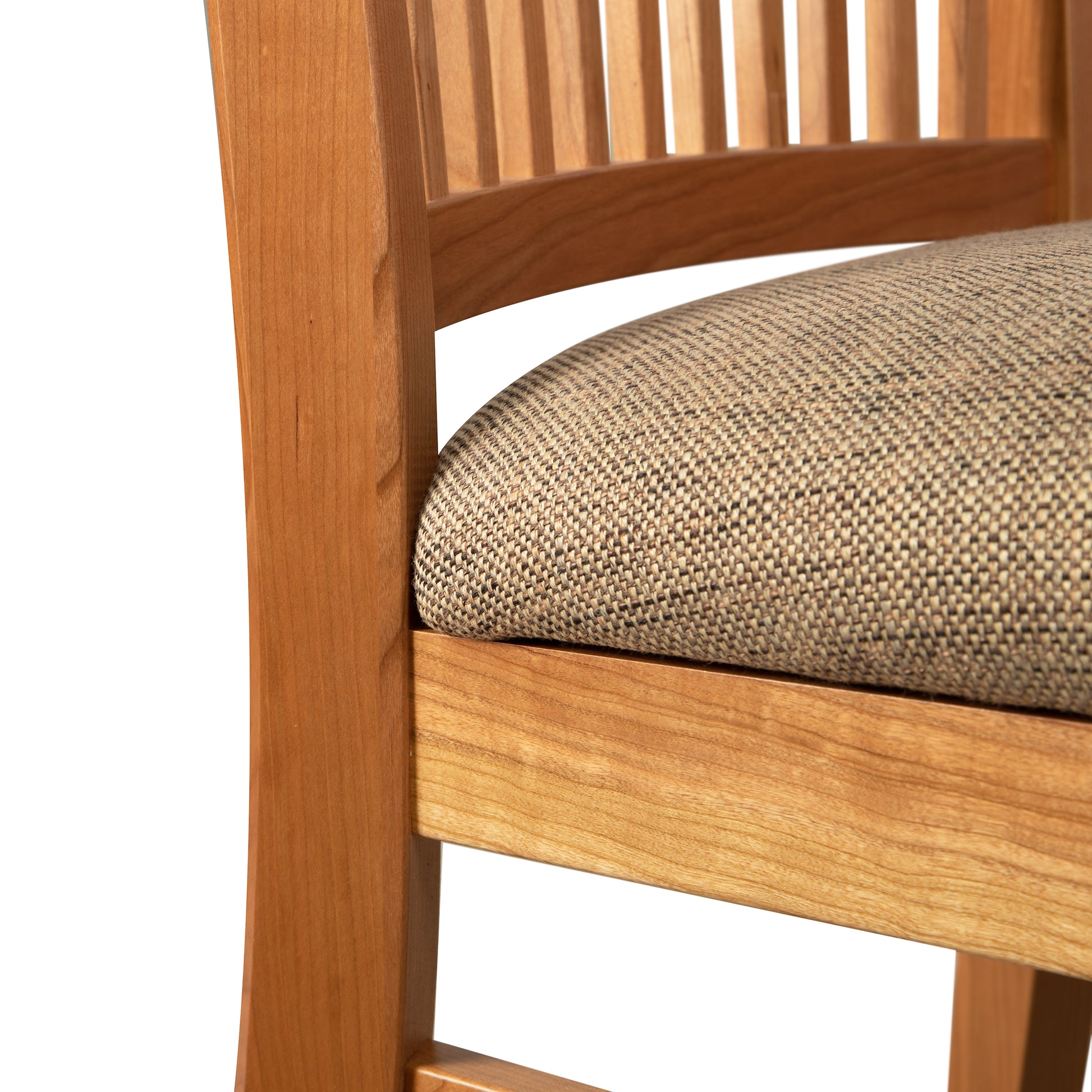 A close up of a wooden chair with a tan upholstered seat.
