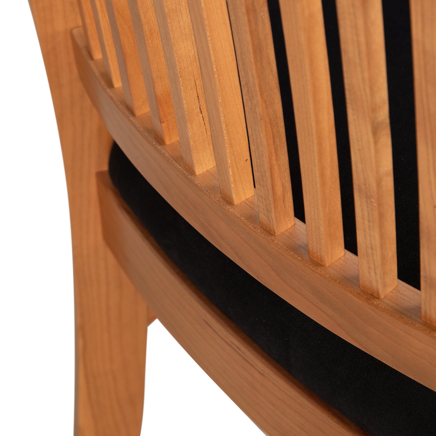 Close-up image of the back of a Contemporary Shaker Side Chair with vertically aligned, evenly spaced slats. The chair, part of Vermont Woods Studios collection, features a curved design. Below the slats, a black cushioned seat is partially visible. The light, natural finish highlights its sustainably handcrafted wood.