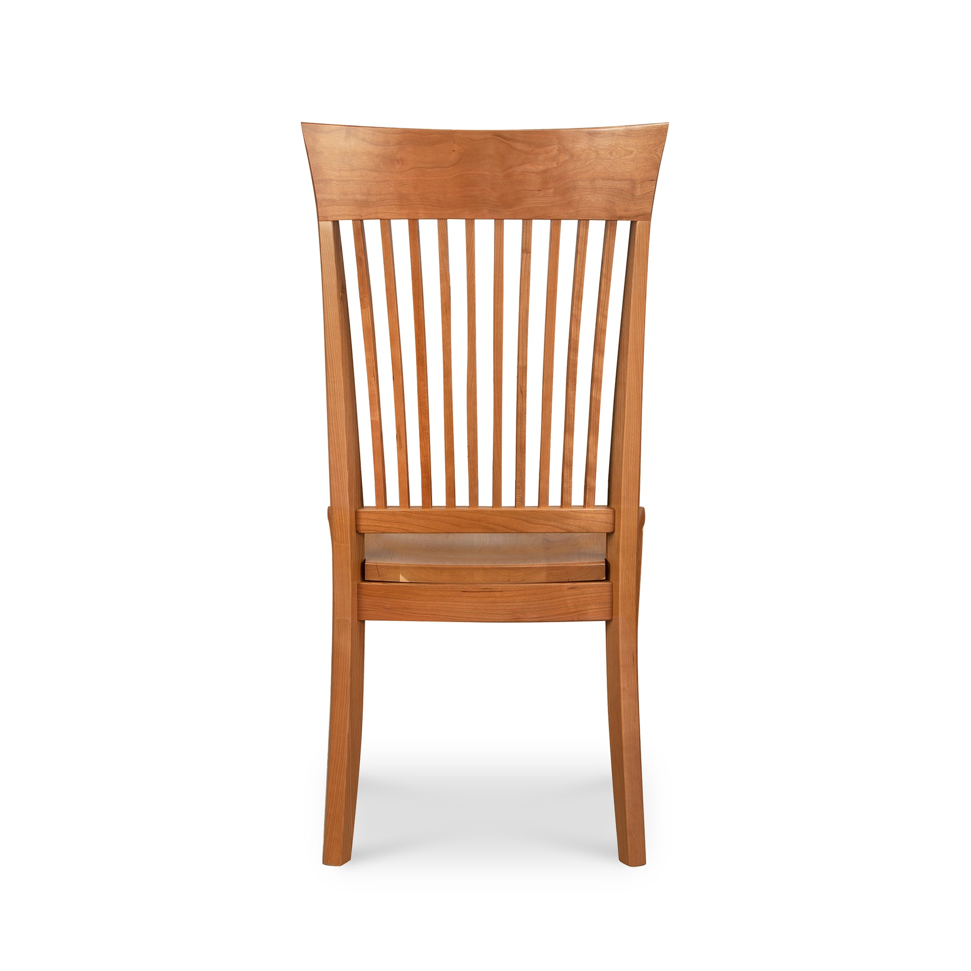 This Contemporary Shaker Side Chair with a wood seat, a display model by Vermont Woods Studios, features a natural cherry finish. Viewed from the back, it boasts a solid backrest with vertical slats and slightly curved legs. The seat appears flat and level, complemented by the horizontal slat just below it.