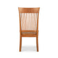 A Vermont Woods Studios Contemporary Shaker Chair with Wood Seat, featuring a high, slightly curved backrest with vertical slats and a scooped wooden seat, presented against a white background.