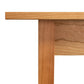 A close-up image of the Country Shaker Dining Table - 36"x60" by Vermont Woods Studios. The discontinued design showcases light-colored wood with visible grain running along the length of the leg and edge of the natural wood top. This ready-to-ship dining table features a simple and minimalist design, customizable to your preference.