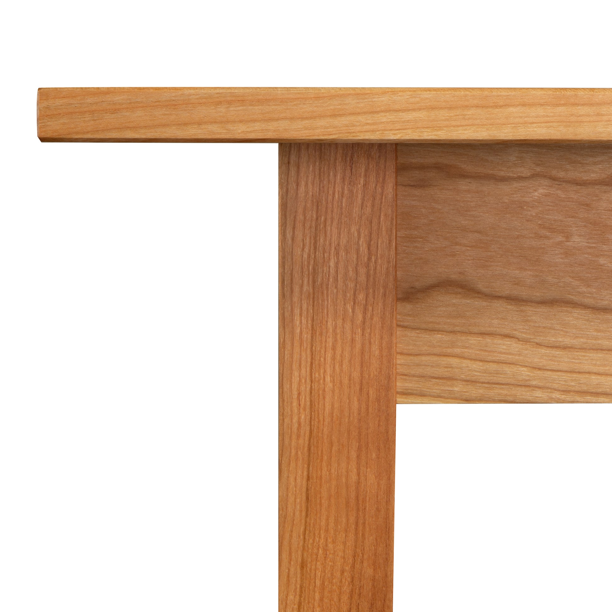 A close-up image of the Country Shaker Dining Table - 36"x60" by Vermont Woods Studios. The discontinued design showcases light-colored wood with visible grain running along the length of the leg and edge of the natural wood top. This ready-to-ship dining table features a simple and minimalist design, customizable to your preference.