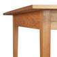 Close-up of the corner of a wooden table by Vermont Woods Studios. The image focuses on the legs and underside of the natural wood top, showcasing its light, natural finish and smooth design. The grain is visible. This customizable Country Shaker Dining Table - 36"x60" stands against a plain white background and is a discontinued design that is ready to ship.