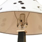 Rock River Studio Dance of Life Table Lamp showcasing its detailed socket, harp, and uniquely patterned white shade with black accents.