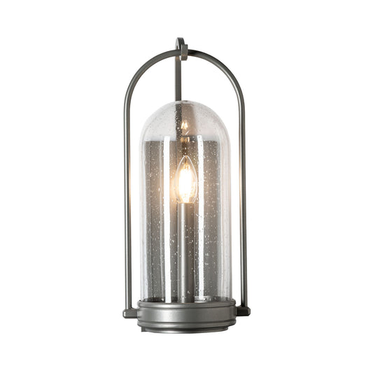 Davis Small Outdoor Sconce by Hubbardton Forge with hand-forged steel frame, clear glass dome, and single exposed bulb, highlighting its elegant craftsmanship.