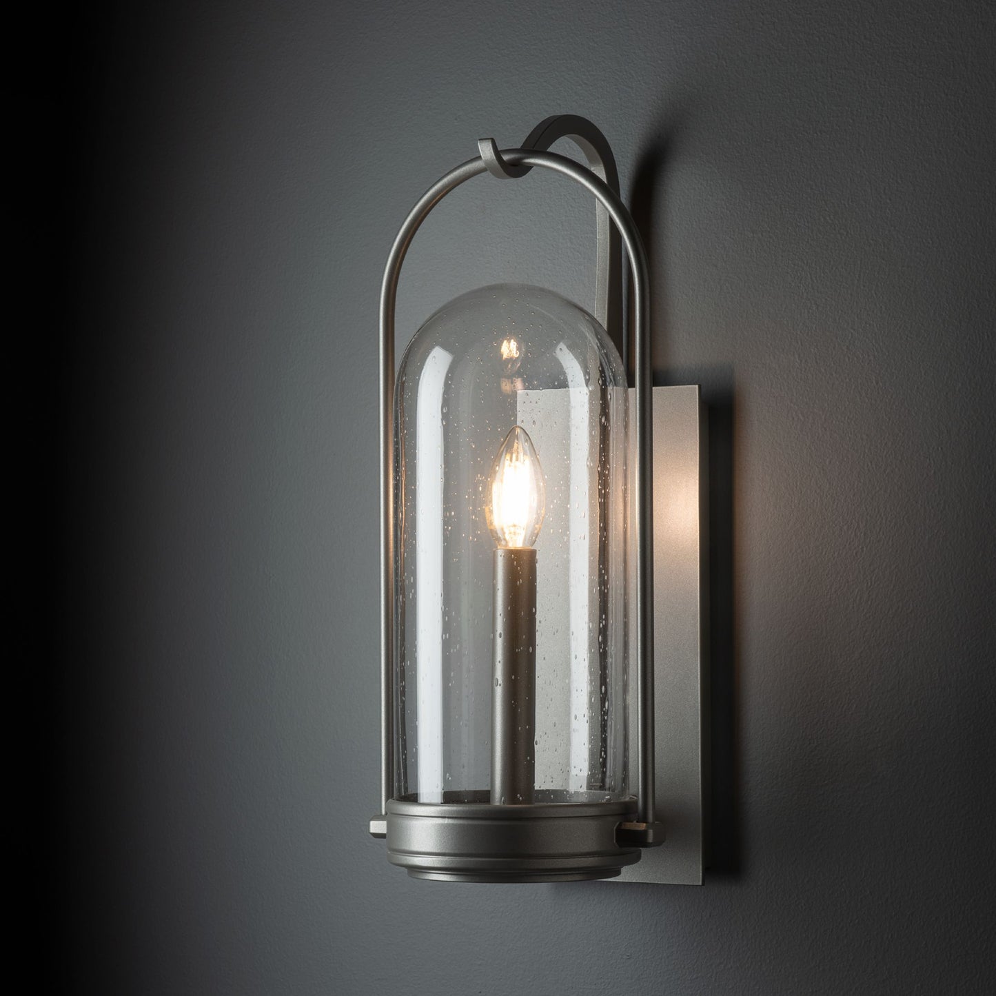 Davis Small Outdoor Sconce featuring a hand-forged steel base, clear glass dome, and single bulb, handcrafted by Hubbardton Forge.