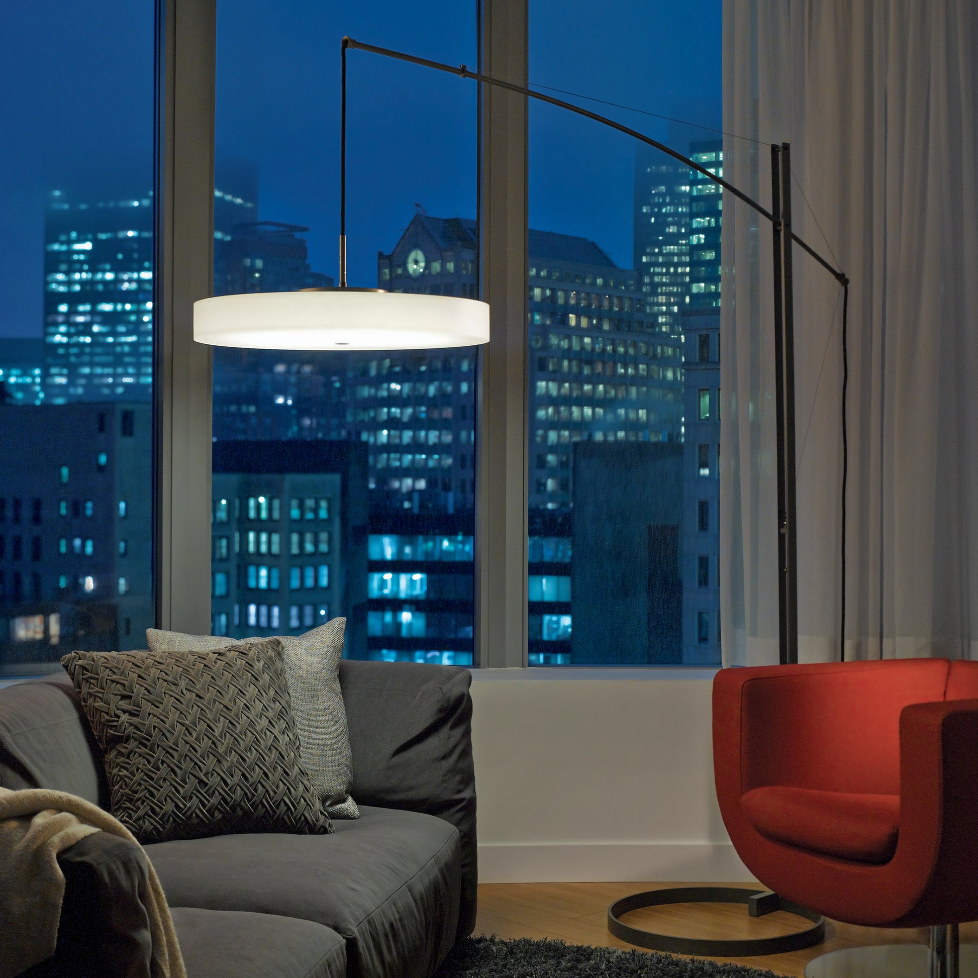 A Hubbardton Forge Disq Arc Floor Lamp in a living room illuminating the space with innovative lighting.