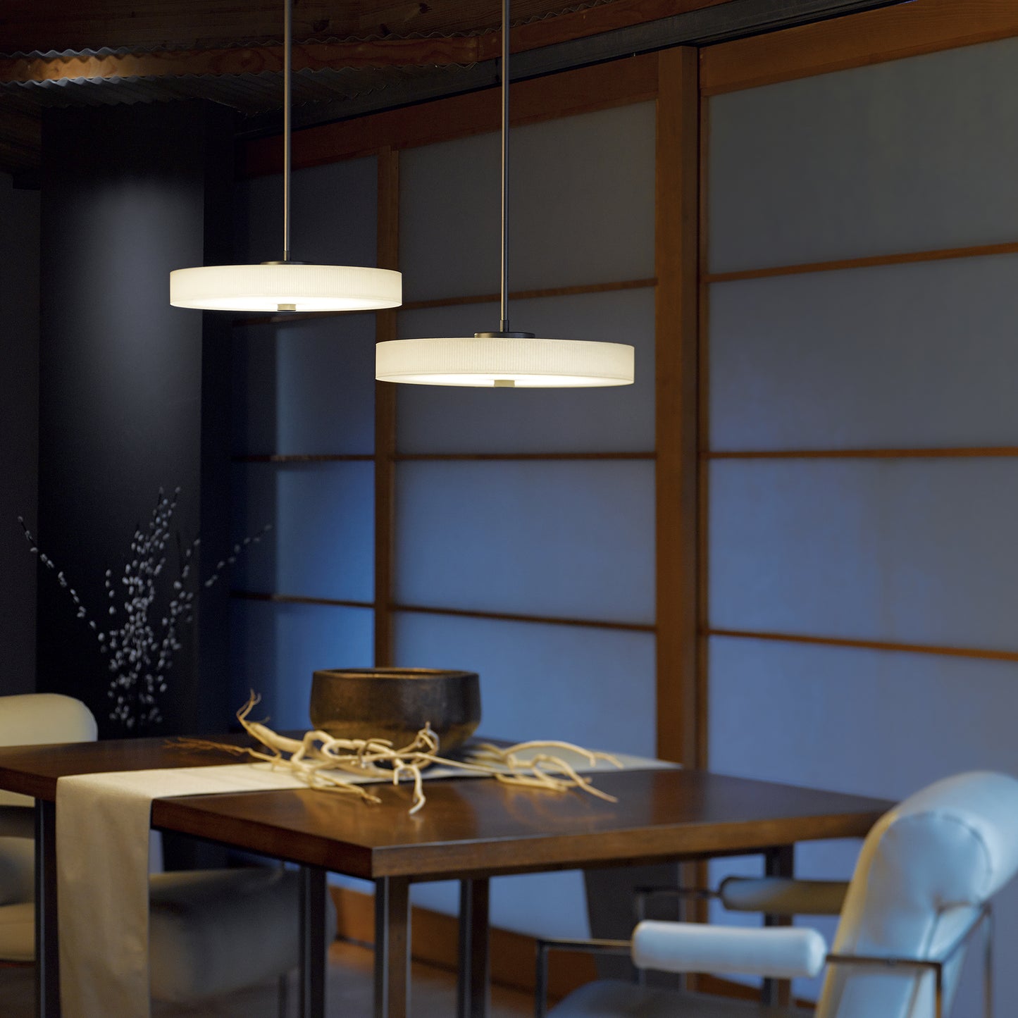 A dimmable LED light source illuminates a dining room with a table and chairs, complemented by the elegant Hubbardton Forge Disq Pendant and Hubbardton Forge pendant.
