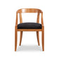 A Vermont Woods Studios Dorset Dining Chair with a curved backrest and a black cushioned seat, isolated on a white background.