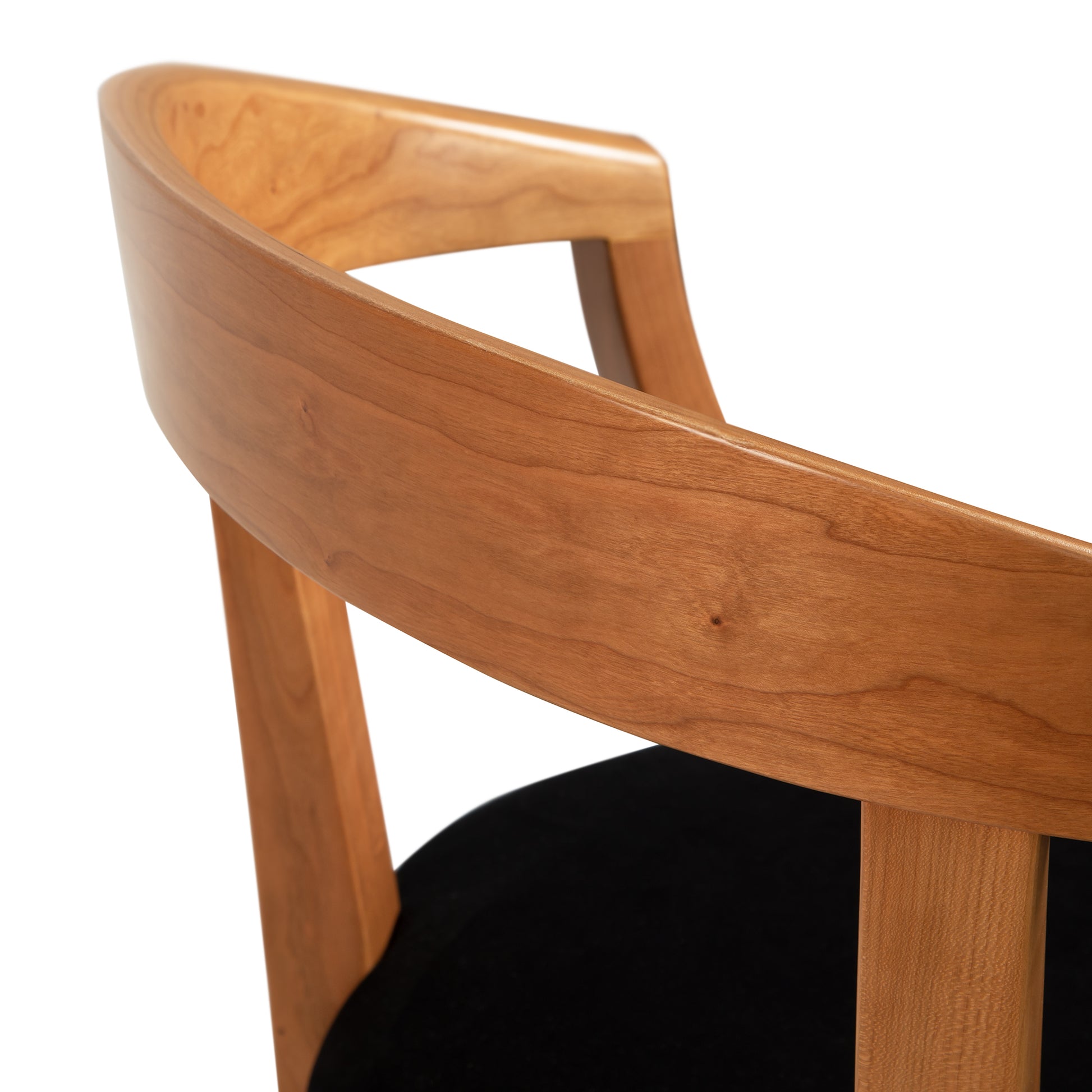 A close up of a wooden chair with a black velvet seat.