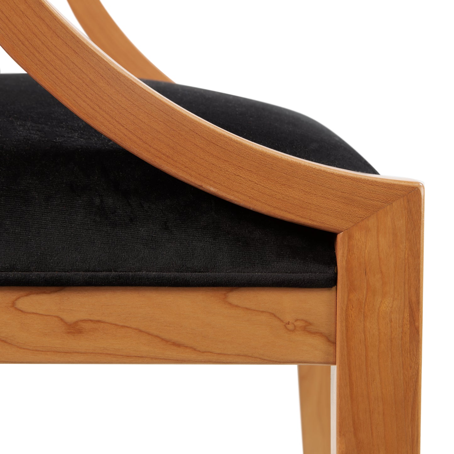 Close-up view of a Dorset Chair by Vermont Woods Studios with a sleek design, featuring a smooth natural cherry frame and black upholstered seat cushion.