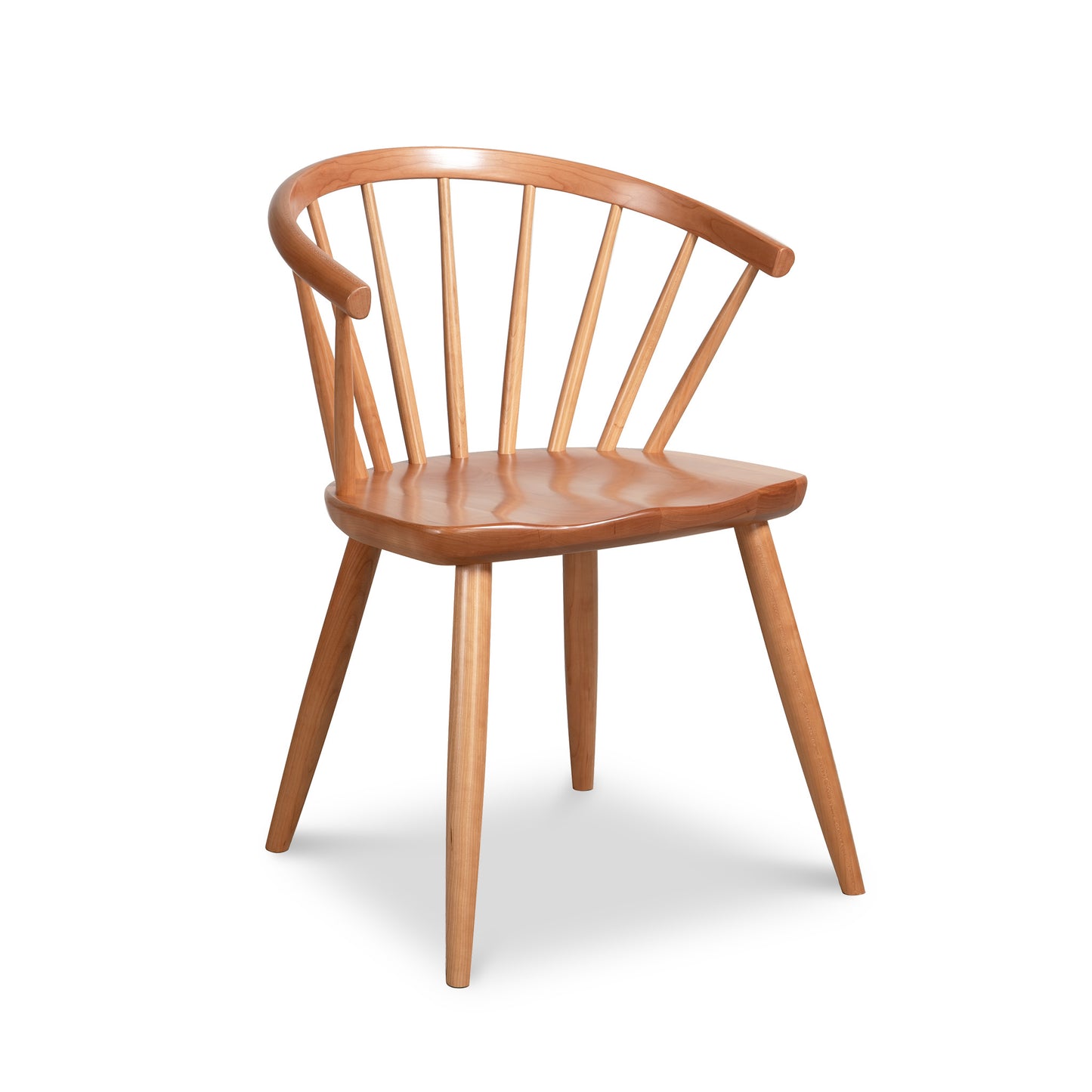 The Dover Curveback Windsor Chair by Vermont Woods Studios is a contemporary wooden chair that features a swooping curved backrest supported by vertical slats and four tapered legs. The solid seat, slightly curved for comfort, showcases a natural wood finish that highlights the grain. Positioned against a plain white background, this chair epitomizes modern elegance.