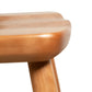 A close-up view showcases the Dover Curveback Windsor Chair from Vermont Woods Studios. This piece, crafted from polished light brown wood with a smooth finish, features rounded edges and legs. The seat and part of one leg are visible against the white background, highlighting its traditional Windsor-style design.