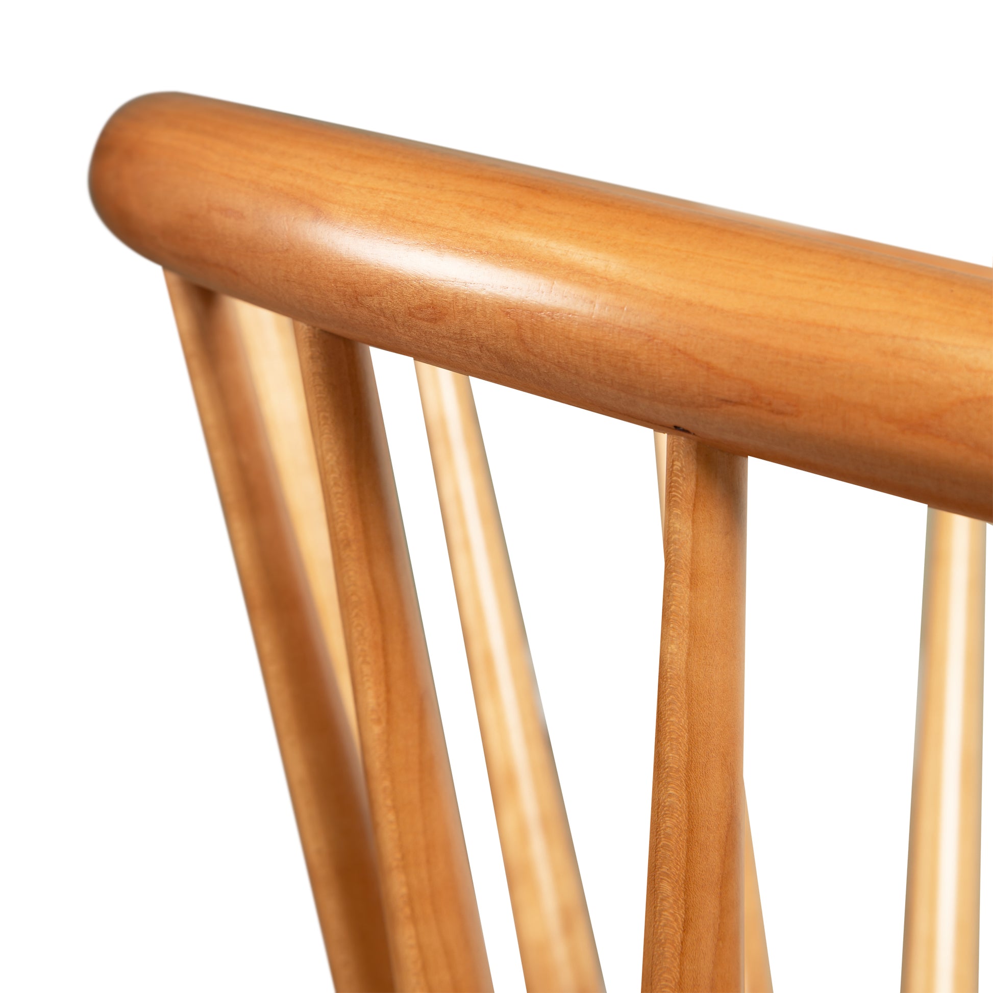 Close-up of the Dover Curveback Windsor Chair - Display Model from Vermont Woods Studios backrest, showcasing its vertical slats and rounded top rail. This eco-friendly solid wood chair has a smooth finish with a natural light brown hue, combining style with an ergonomic seat back.