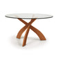 A Entwine Round Glass Top dining table with a sustainably sourced cherry wood base featuring intersecting legs on a white background.