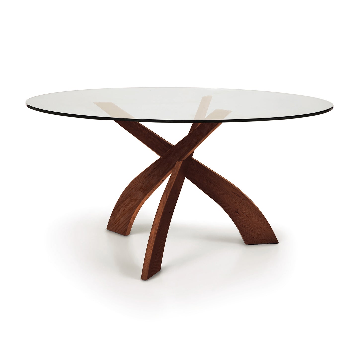 Entwine Round Glass Top Dining Table by Copeland Furniture with an intersecting sustainably sourced cherry wood base on a white background.