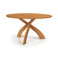Entwine Round Solid Top Table by Copeland Furniture showcases cherry wood and unique intersecting curved legs, highlighting its American craftsmanship.
