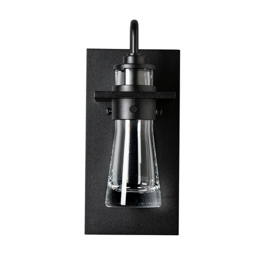 Close-up of the Erlenmeyer Medium Outdoor Sconce by Hubbardton Forge, highlighting its sturdy black frame and clear glass industrial design.