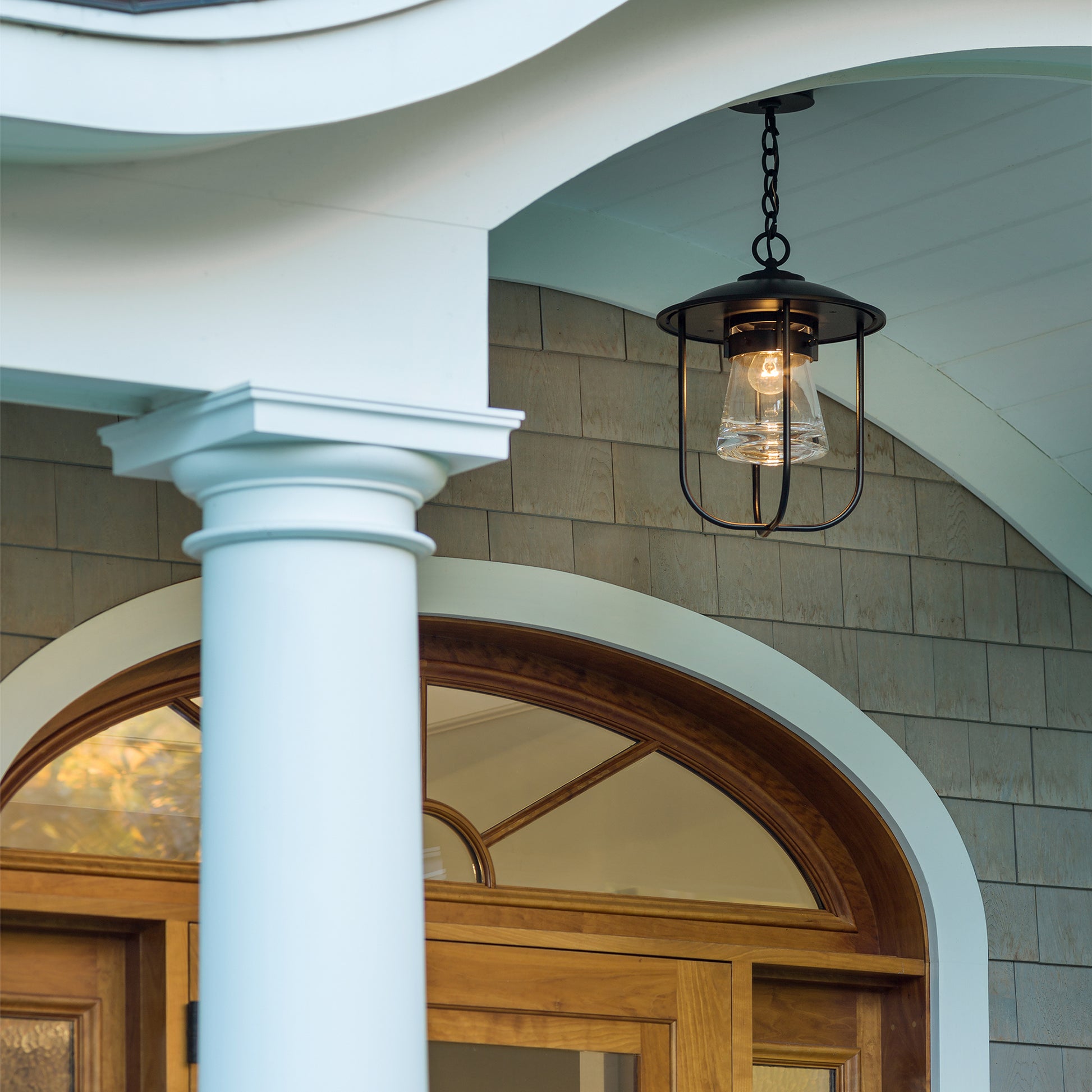 Close-up of the Hubbardton Forge Erlenmeyer Outdoor Pendant, a high-quality, American-made lighting fixture on a porch.