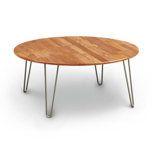 Essentials Round Coffee Table by Copeland Furniture with natural cherry wood and metal legs on a white background.