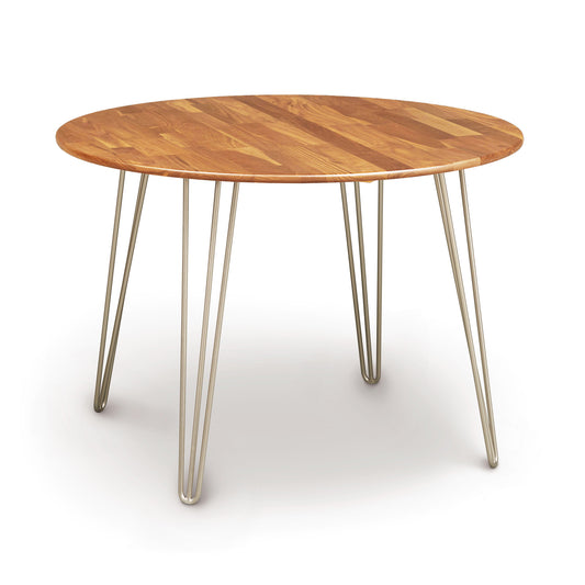 A mid-century modern Essentials Round Dining Table by Copeland Furniture with metal legs and a wooden top.